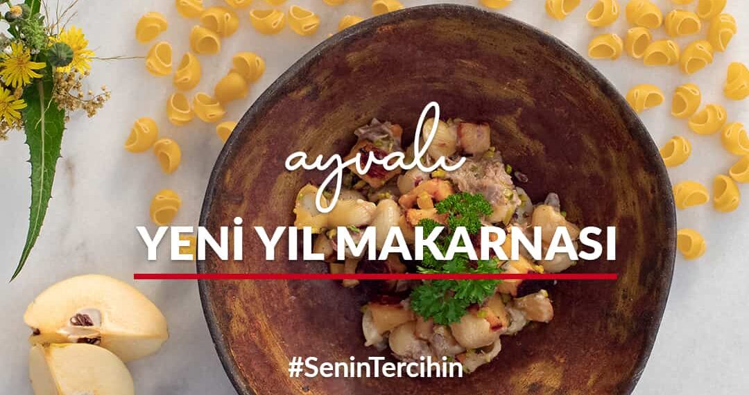 Mermer tezgah üstünde yer alan tabakta ayvalı yeni yıl makarnası; çevresinde taze sarı yeşil çiçek, pişirilmemiş mantı makarnalar, dilim halinde ayva