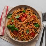Tabağın içindeki spaghetti, domates ve yeşillikler