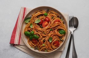 Tabağın içindeki spaghetti, domates ve yeşillikler