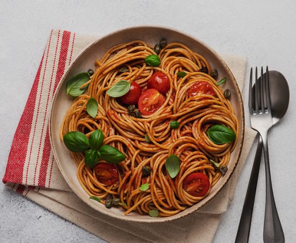 Tabağın içindeki spaghetti, domates ve yeşillikler